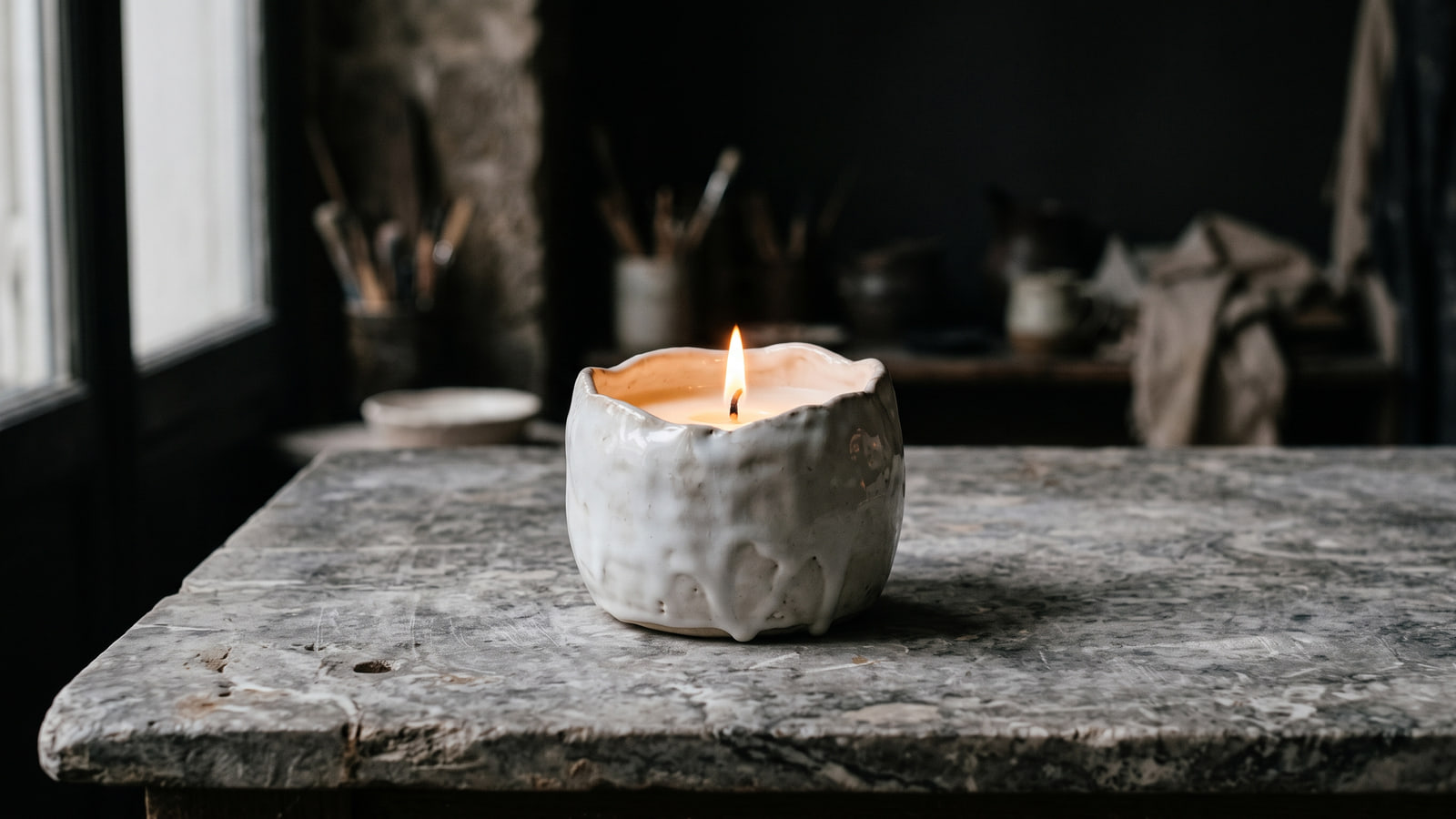 Astier de Villatte style white glazed ceramic candle on a Parisian marble table